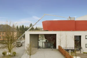 57 m Hybrid Hubarbeitsbühne im Einsatz über Hindernisse an Gebäude hinweg.